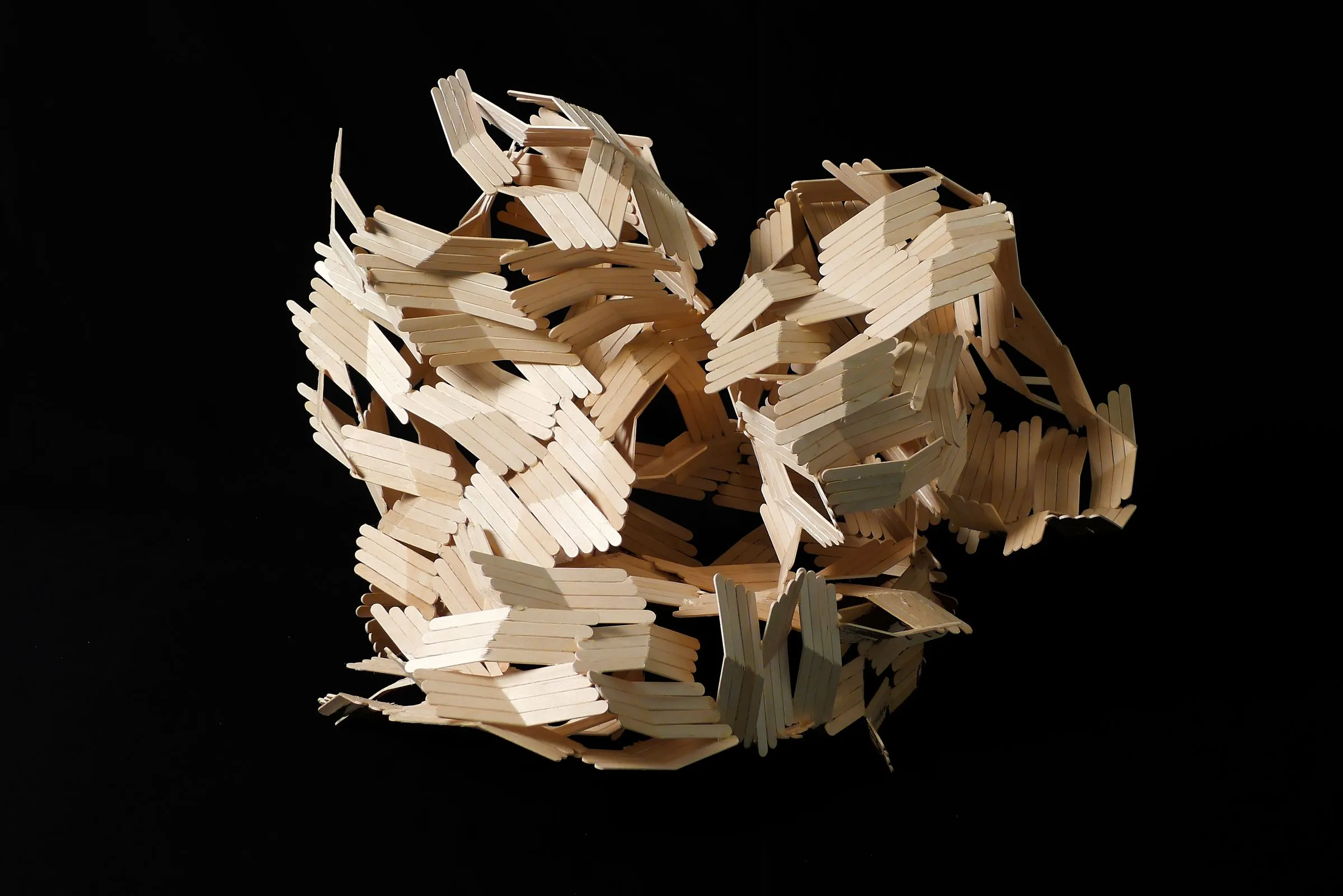 An aggregate model of thin folded card strips photographed against black