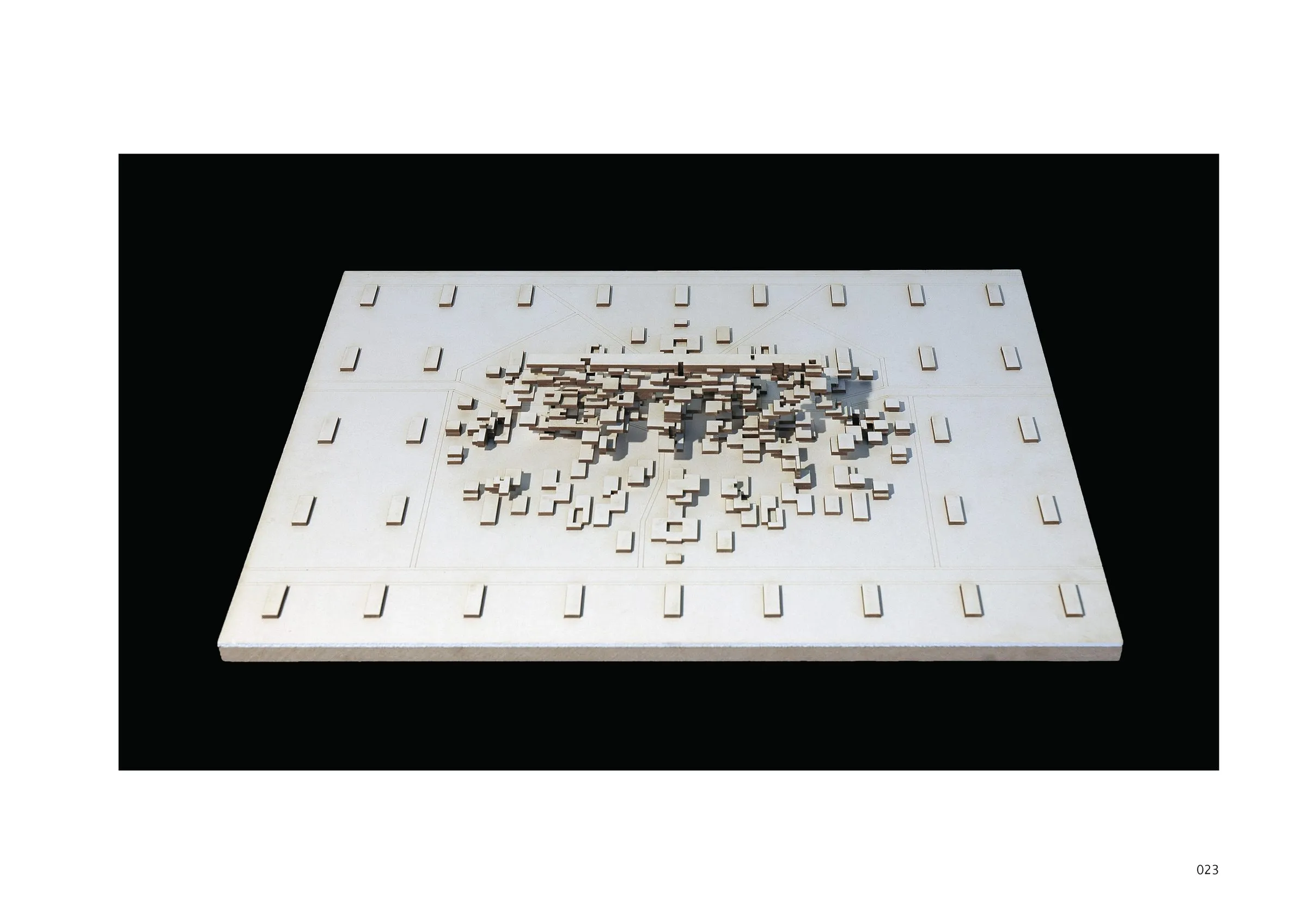 A white model board on which small blocks form a gradient from a single house to a long slab