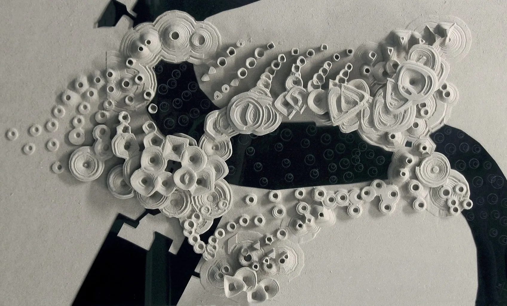 Photograph of a white model: paper rings and cups clustered on a dark board