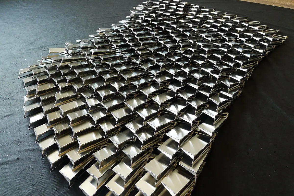 A curved shell assembled from hundreds of identical silver panels, photographed on a table