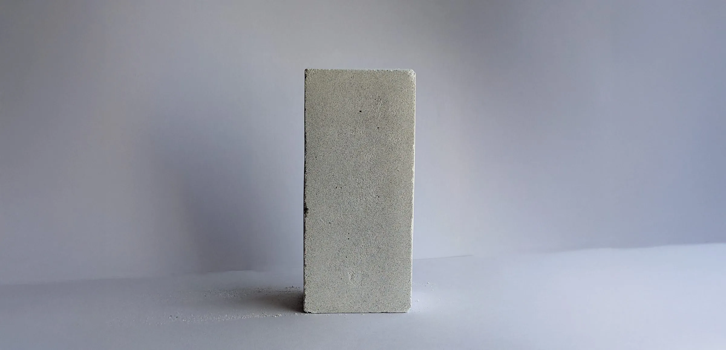A pale sun-cured brick of the calcium silicate standing upright on a white surface