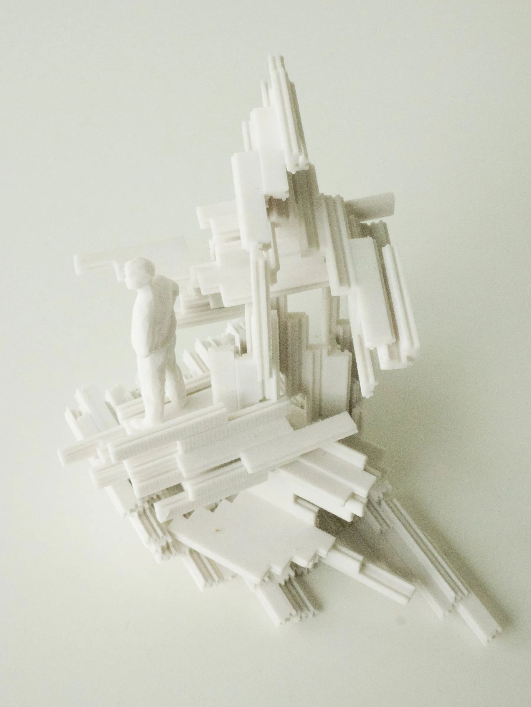 The white model with a small figure placed on one of the frames, for scale