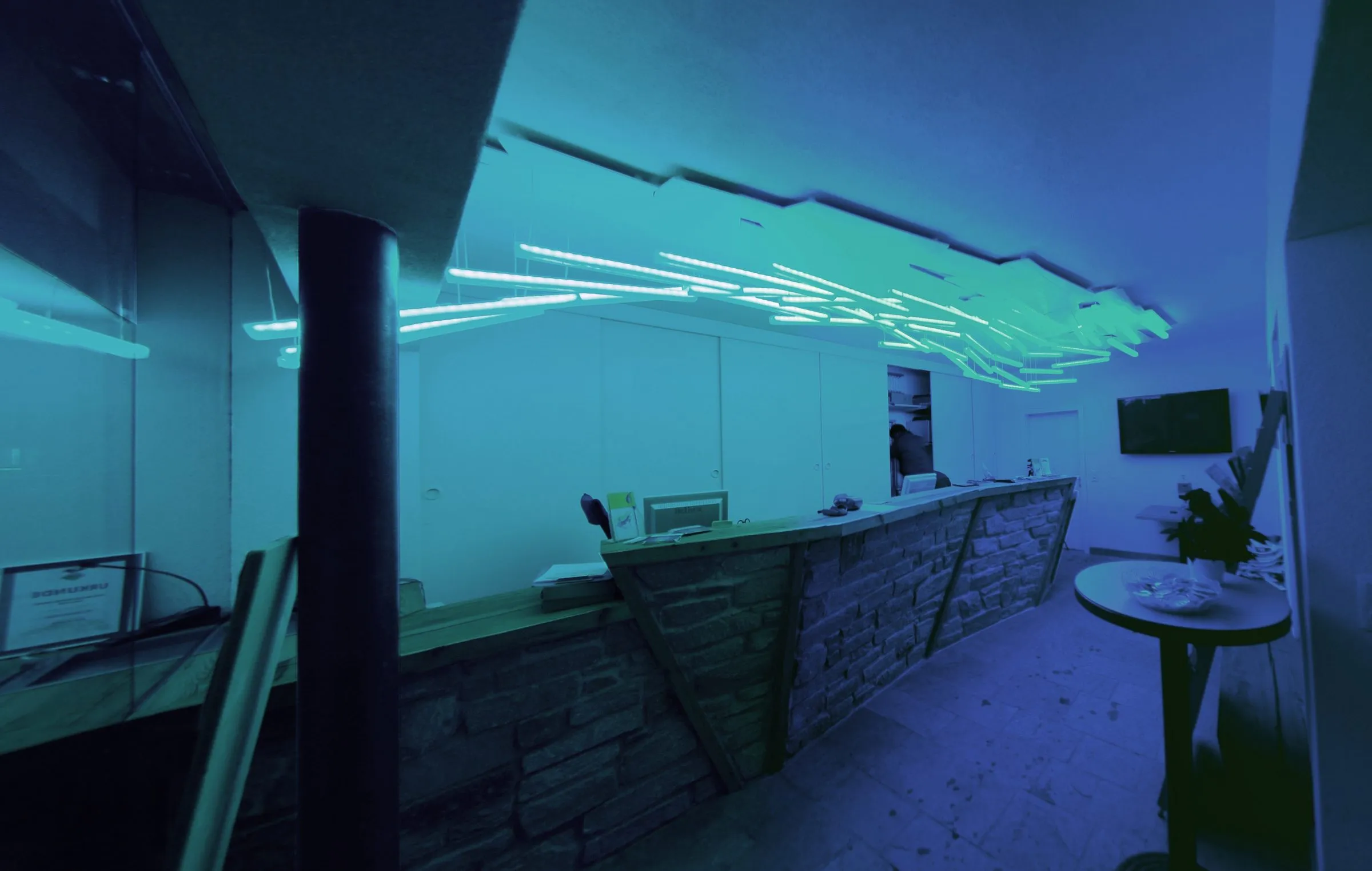 Interior of the ski-school shop: a counter of rough natural stone below a ceiling of white light poles fanning out from the corner of the room