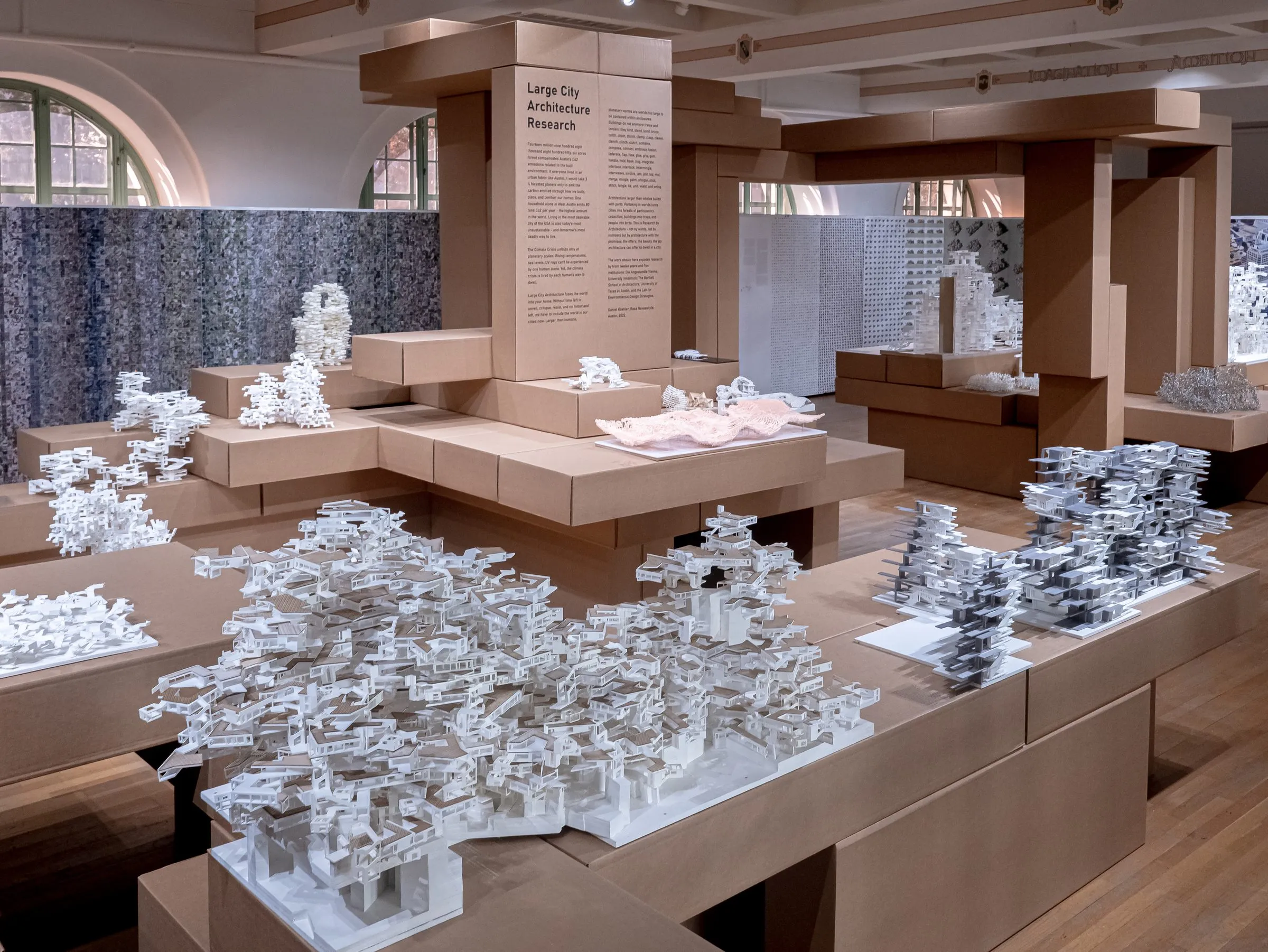 White models on plinths in the Mebane Gallery in front of the printed wall