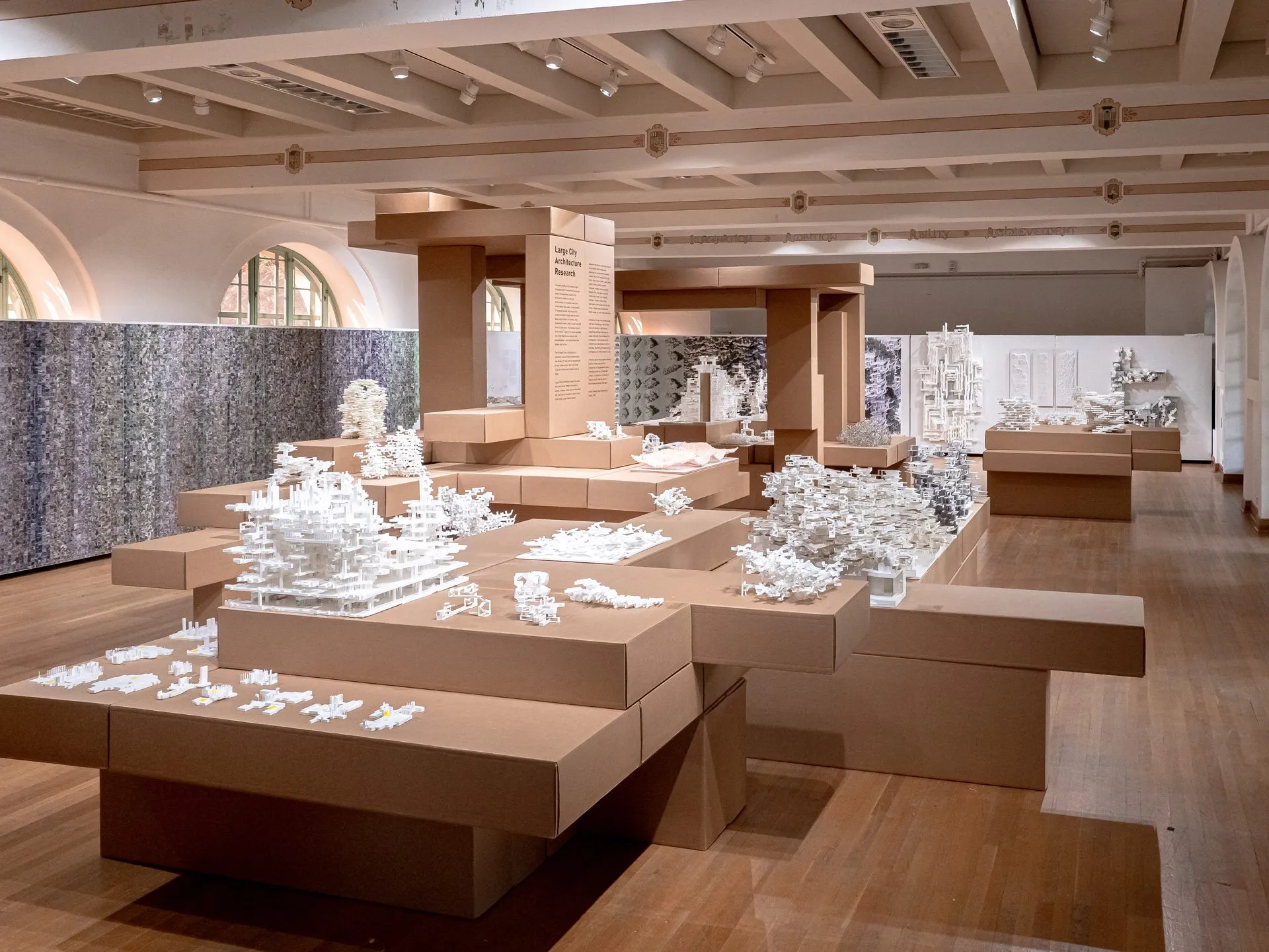 The whole room: cardboard beams and columns, platforms of white models, arched windows behind