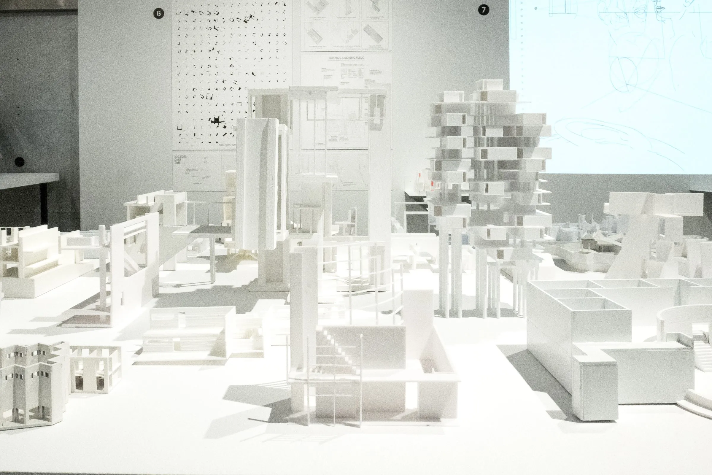 White models installed on a table in front of a printed wall