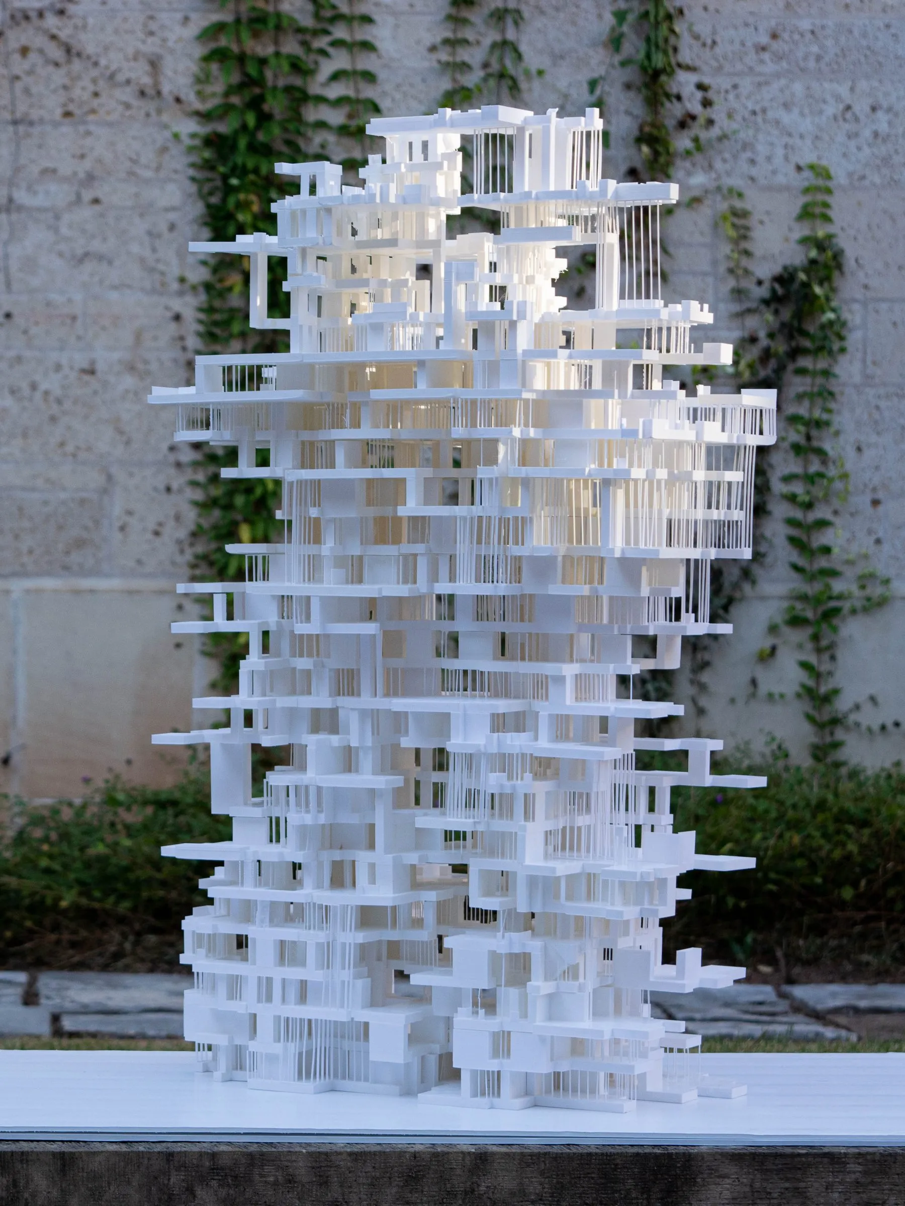 A white tower model standing in daylight in front of an ivy-covered wall