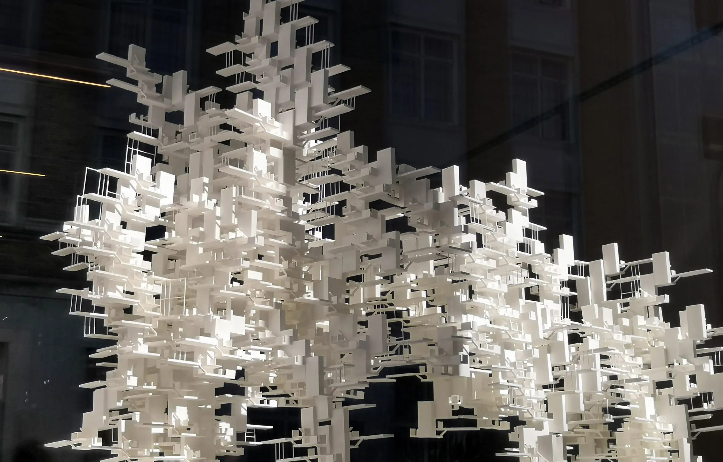A white model of a tower of stacked, interlocking blocks