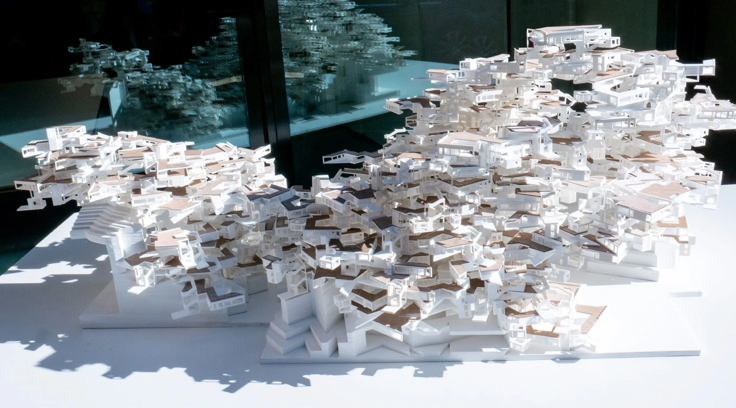 A white stacked model of NPoche on a table in front of a screen