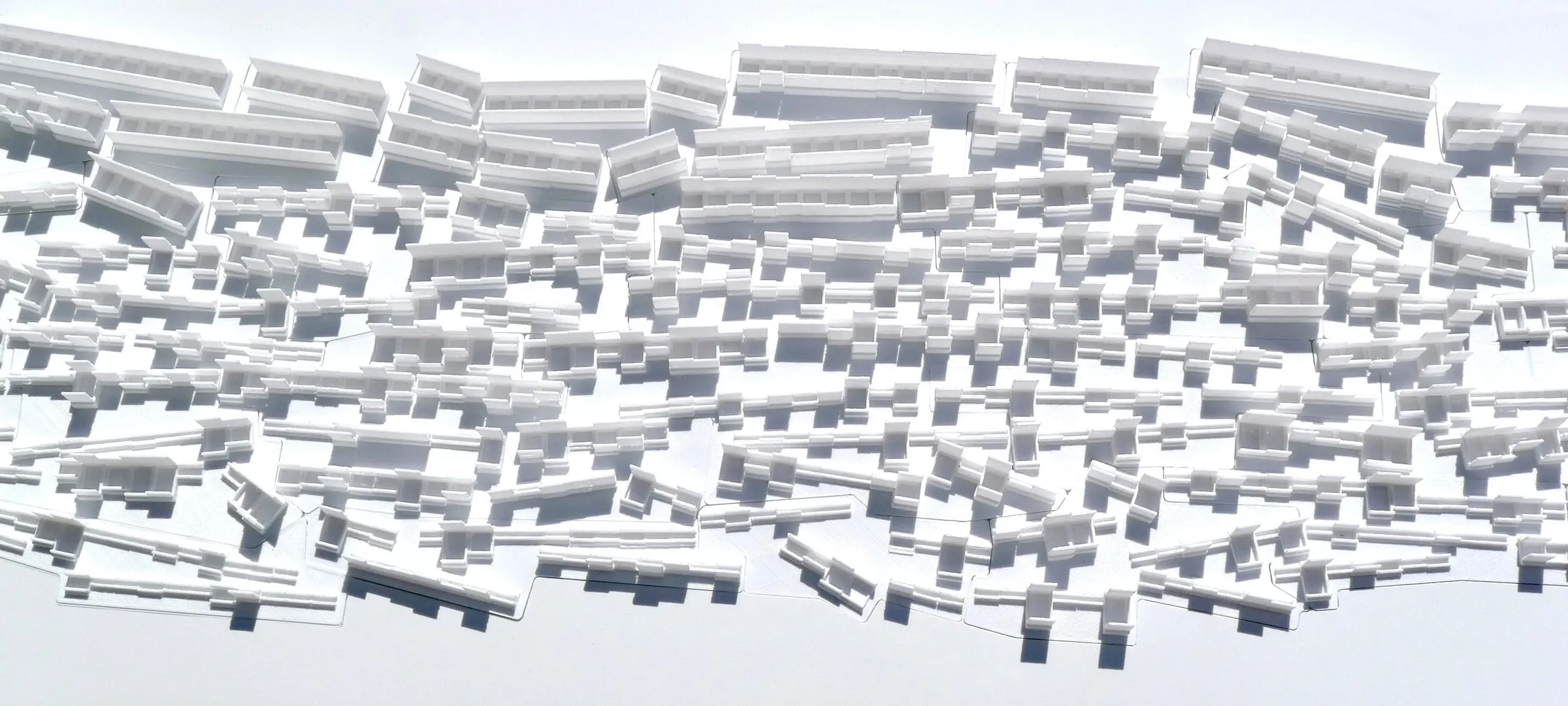 Close view of a white relief: rows of small cells and slabs cast as one surface