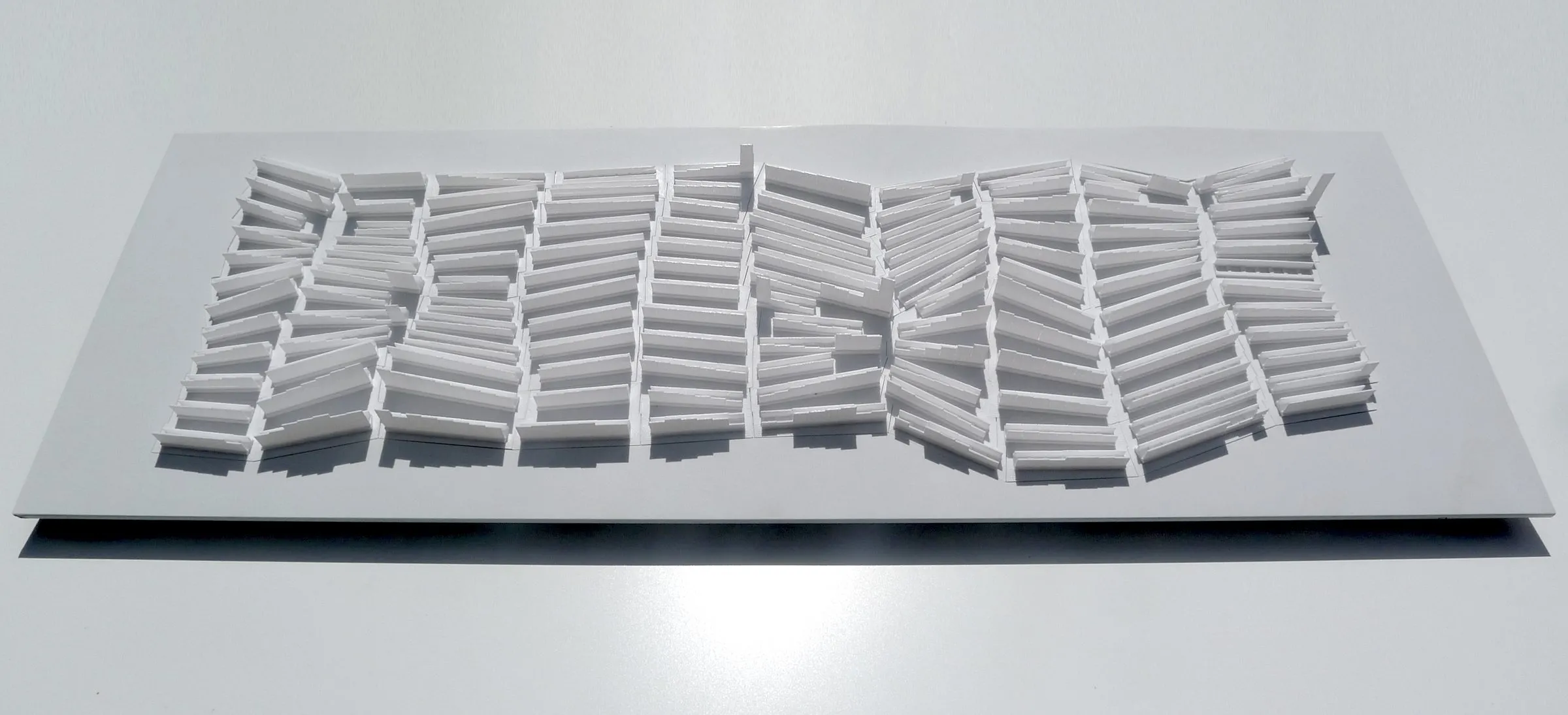 A white relief panel of slab blocks in perspective on a white ground